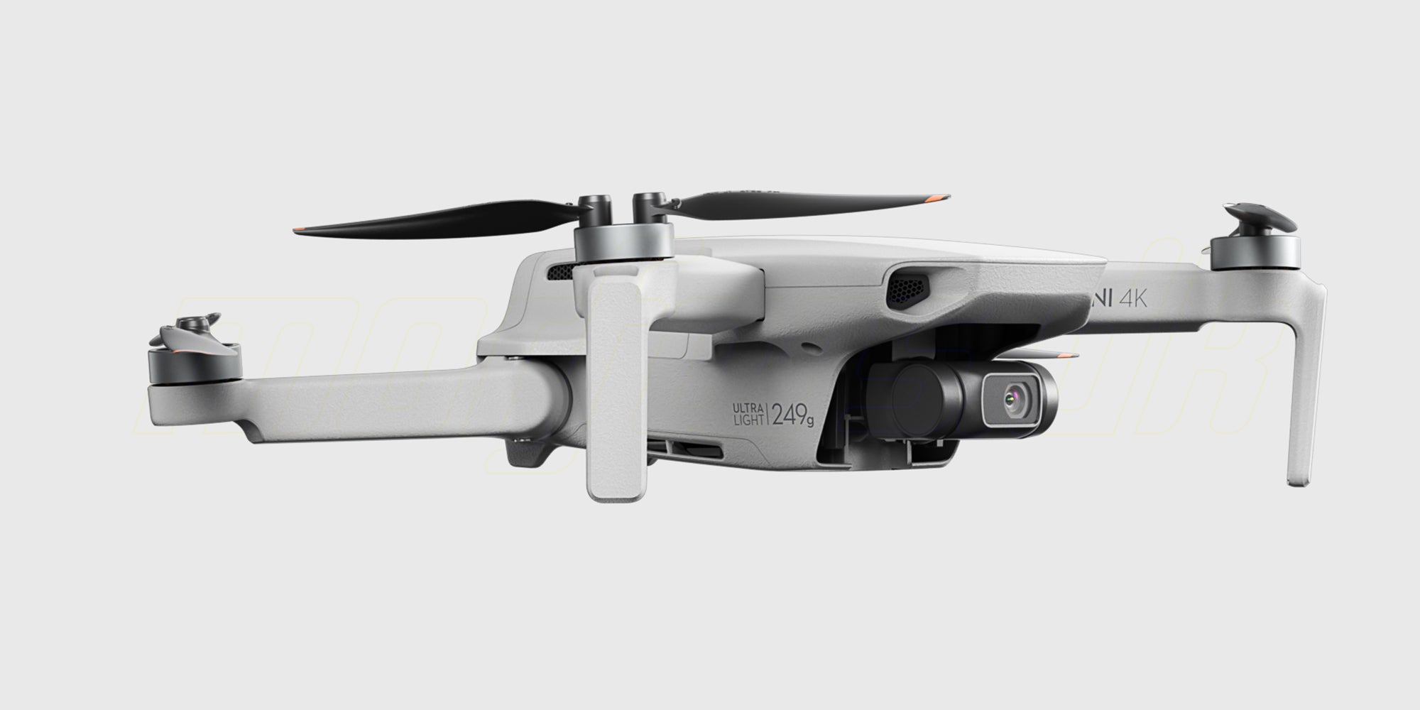 Grå DJI Mini 4K drone fra Fly More Combo pakken vist skråt forfra med foldede arme på hvid baggrund.