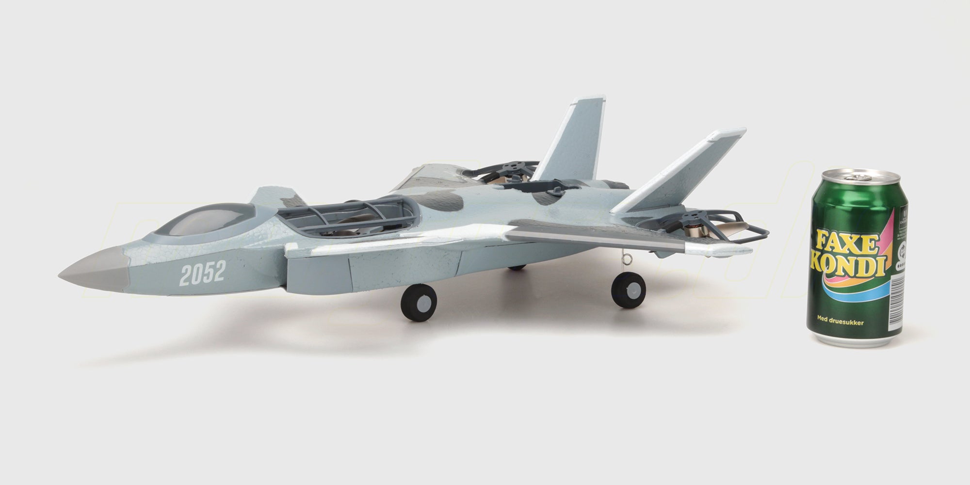 Grå Fighter Jet Brushless fjernstyret fly i luften med detaljeret cockpit og vinger på en klar blå himmel.
