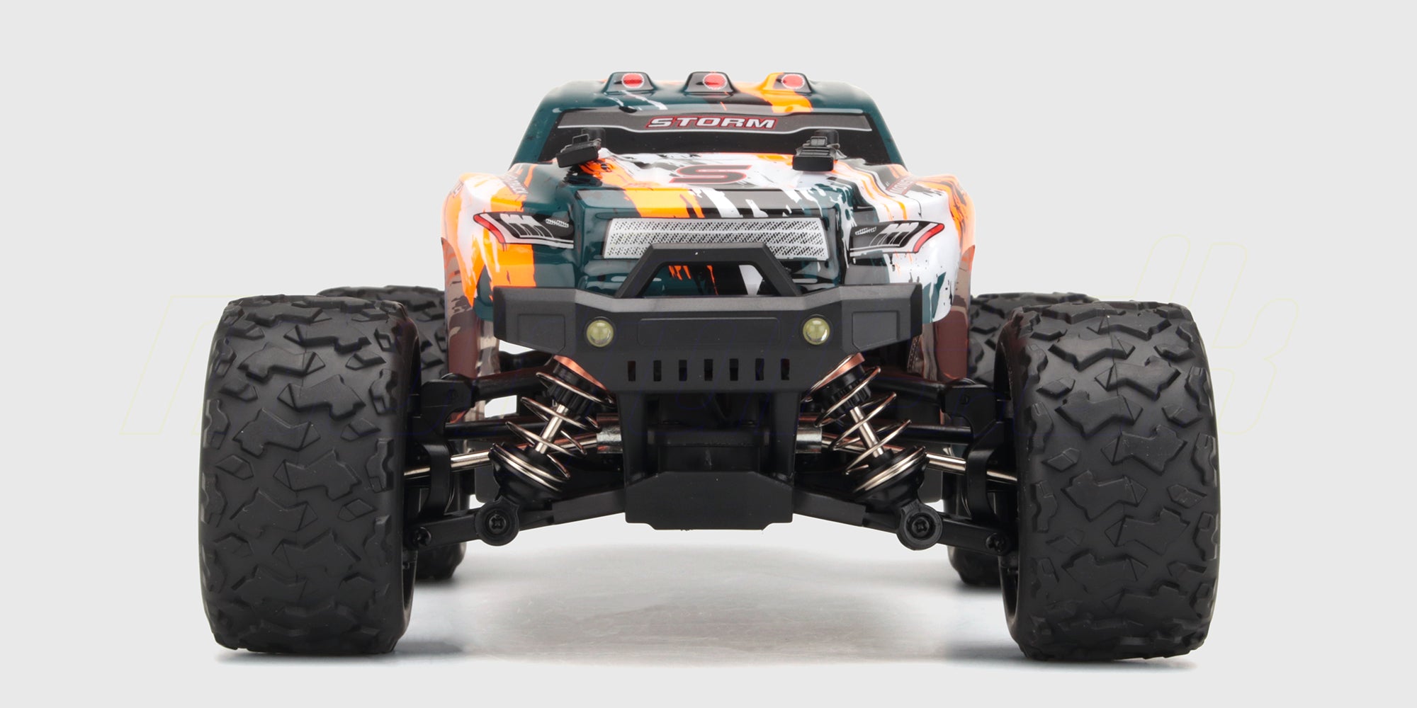 Grøn Hurricane 2.0 fjernstyret truck i fuld fart gennem vandpytter med sprøjt på en grusvej.