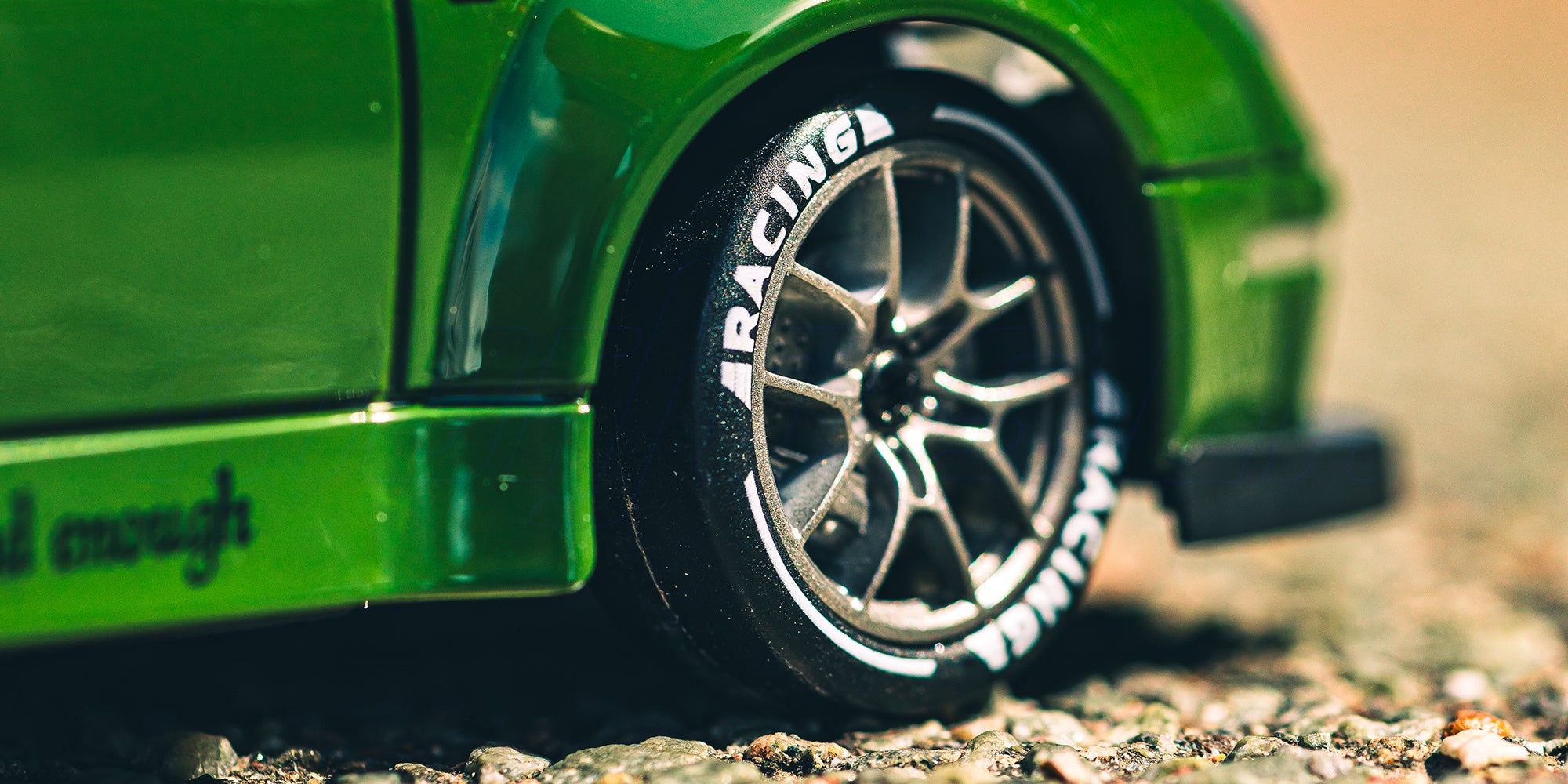 Lille hvid BTD Drifter fjernstyret bil i 1:24 skala vist forfra i et indendørs banemiljø med lys.