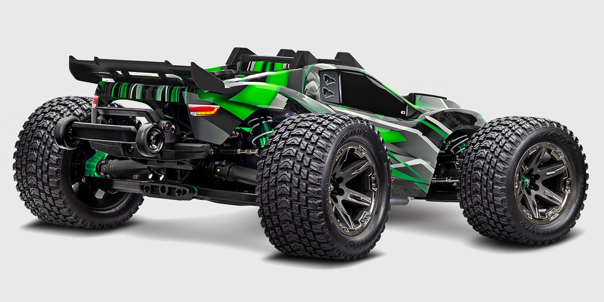 Blå Traxxas Rustler 4x4 Ultimate fjernstyret bil i action, mens den hvirvler støv op i et skarpt sving på grus.