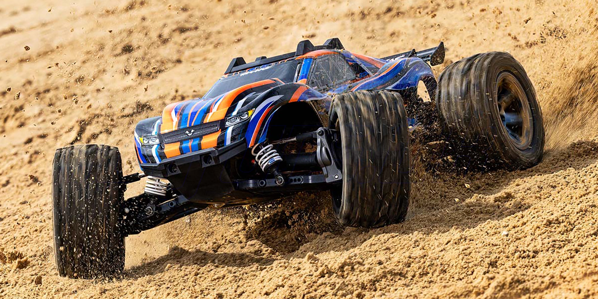 Grøn Traxxas Rustler 4x4 VXL fjernstyret bil i fuld fart på støvet grusvej med opspvirvlende jord.