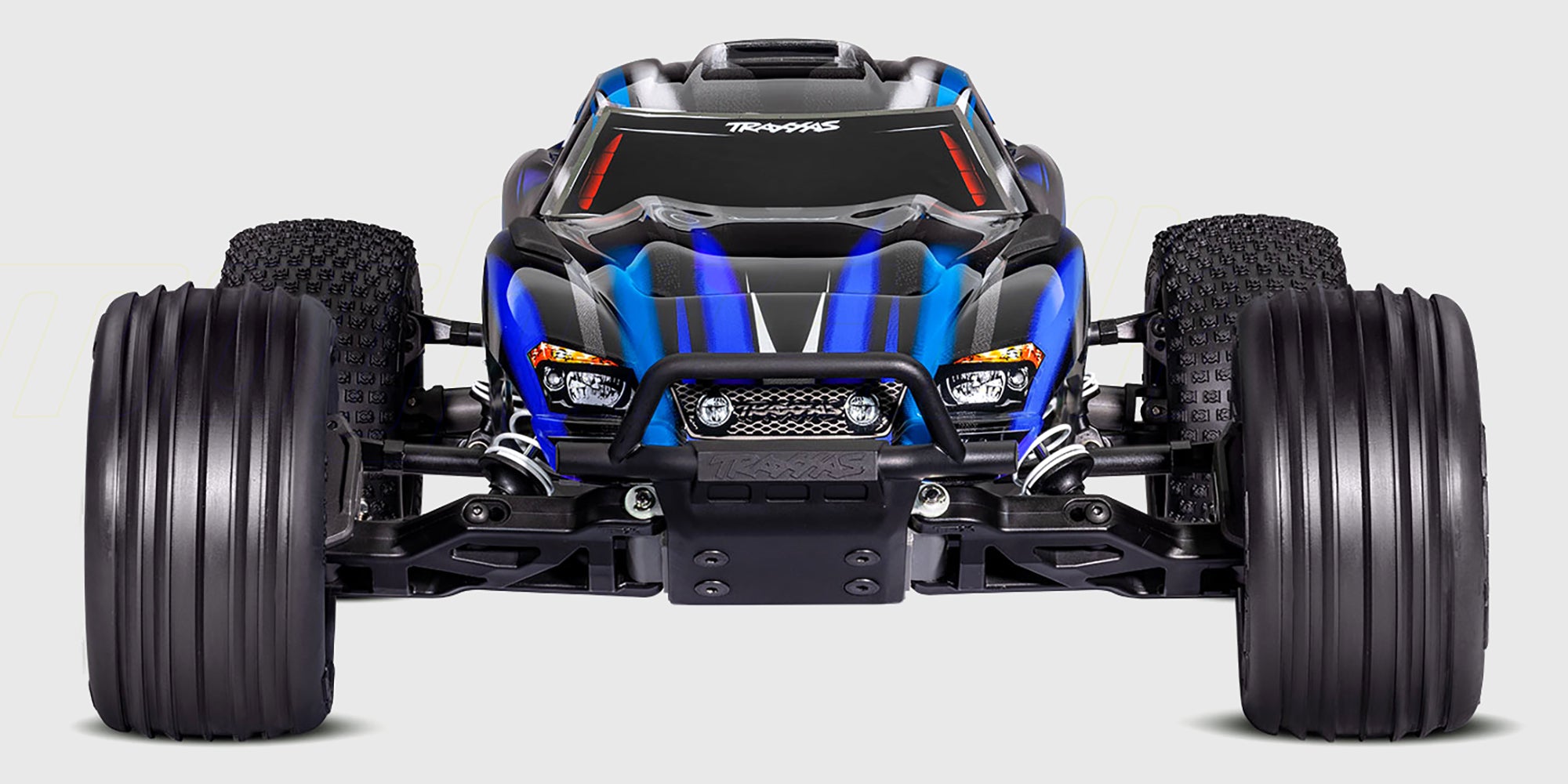 Blå Traxxas Rustler Brushless 2WD stadium truck med grove offroad-dæk vist i profil mod hvid baggrund.