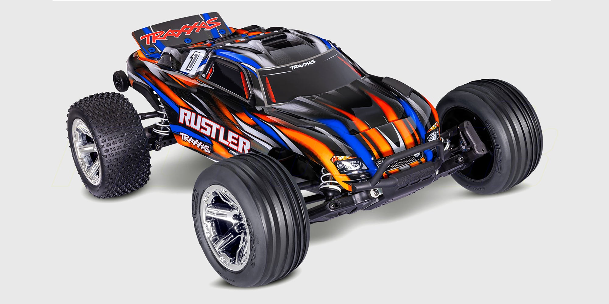 Blå Traxxas Rustler Brushless fjernstyret bil i hurtig kørsel gennem vandpyt med vandsprøjt.