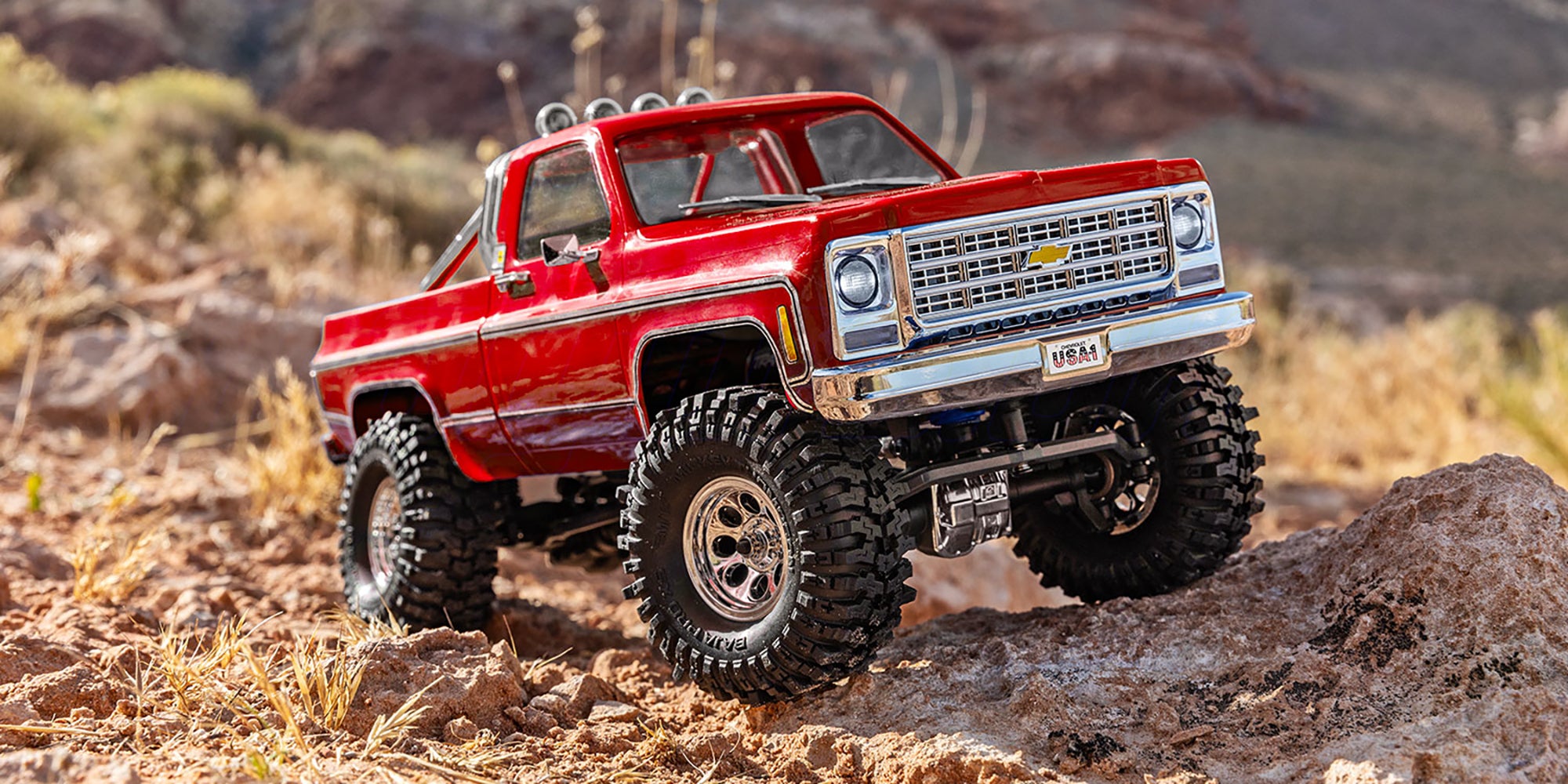 Rød Traxxas TRX-4M Chevrolet K10 High-Trail fjernstyret crawler set fra siden på hvid baggrund.