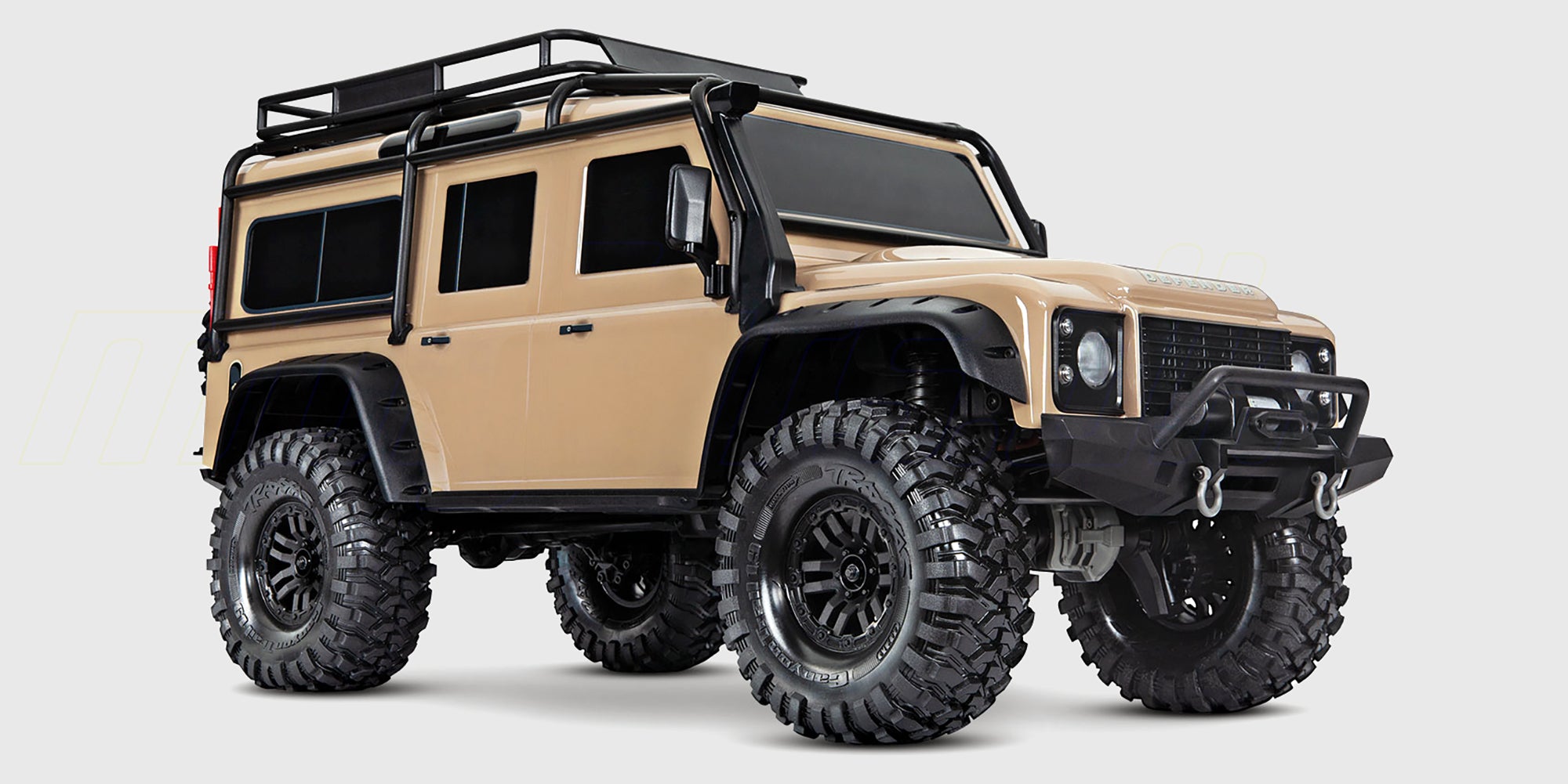 Grå Traxxas TRX-4 Land Rover Defender crawler kører gennem mudret terræn i naturen.