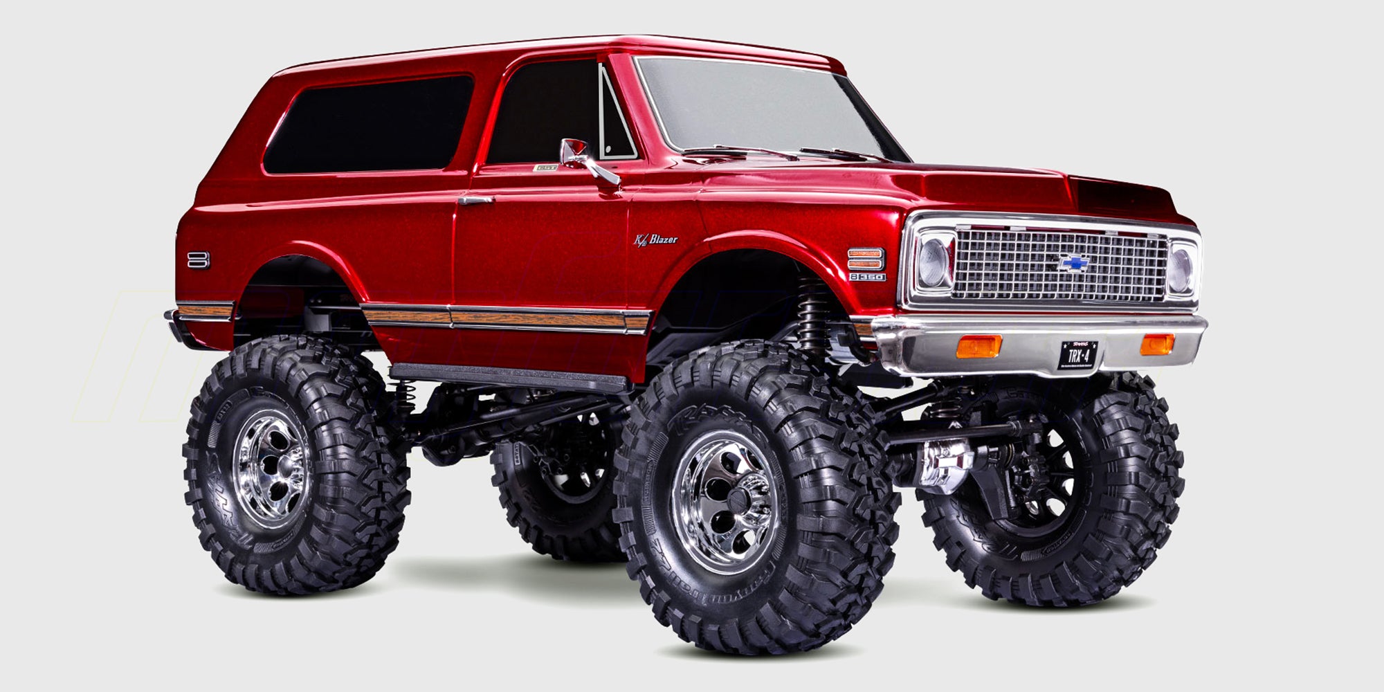 En rød Traxxas TRX-4 Chevrolet K5 Blazer fjernstyret crawler forcerer store sten og ujævnt terræn.