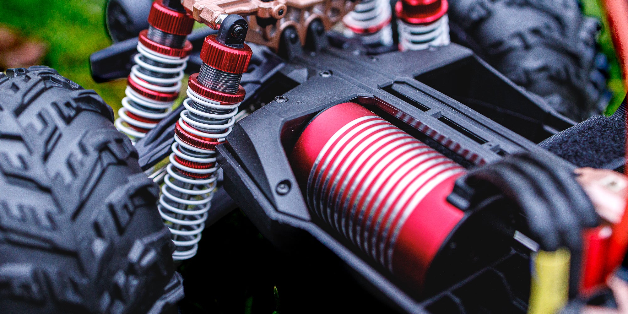 Grøn XLH Race Truck med store dæk kører gennem vandpyt og mudder på en grusvej.