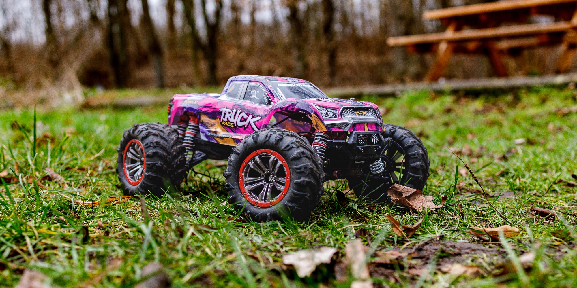 Rød og sort XLH Race Truck fjernstyret bil kører på græs i høj fart.