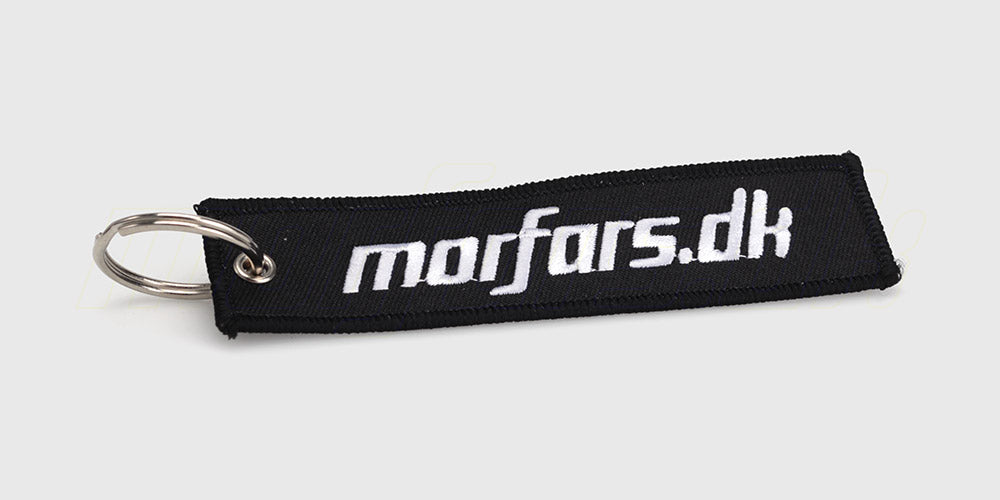 Sort Morfars.dk nøglering med hvidt logo monteret på et bundt nøgler.