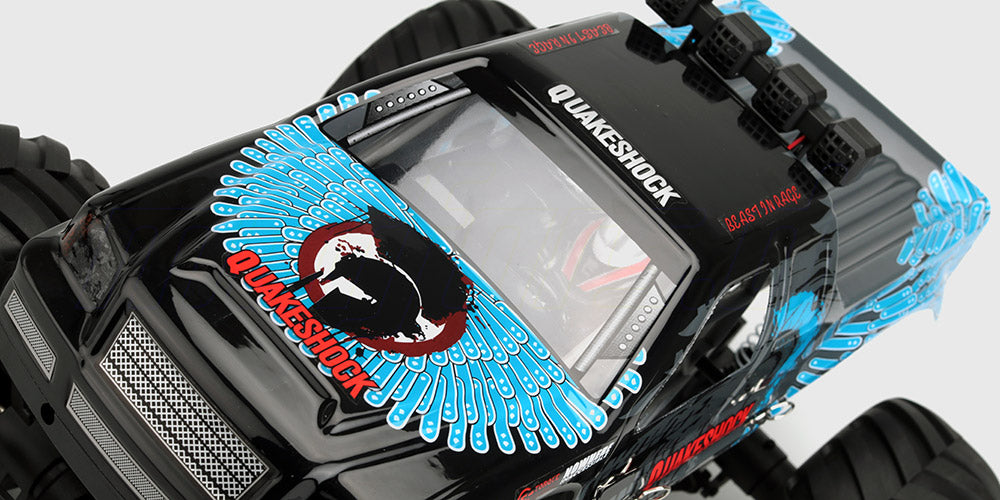 Blå Quakeshock fjernstyret monster truck med 4-hjulstræk og store terrængående dæk på hvid baggrund.