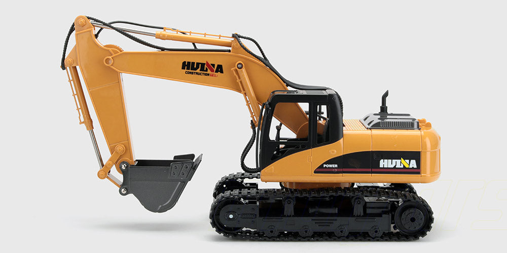 Gul fjernstyret gravemaskine med metalskovl og fjernbetjening vist på en hvid baggrund.