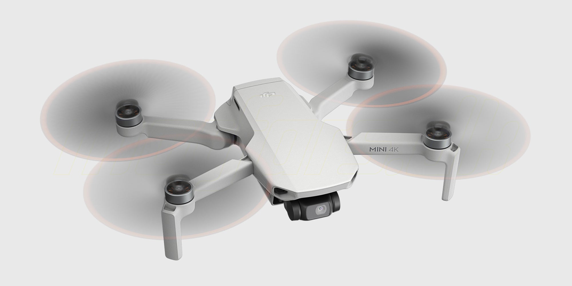 Grå DJI Mini 4K drone fra Fly More Combo pakken set skråt forfra med kameraet i fokus.