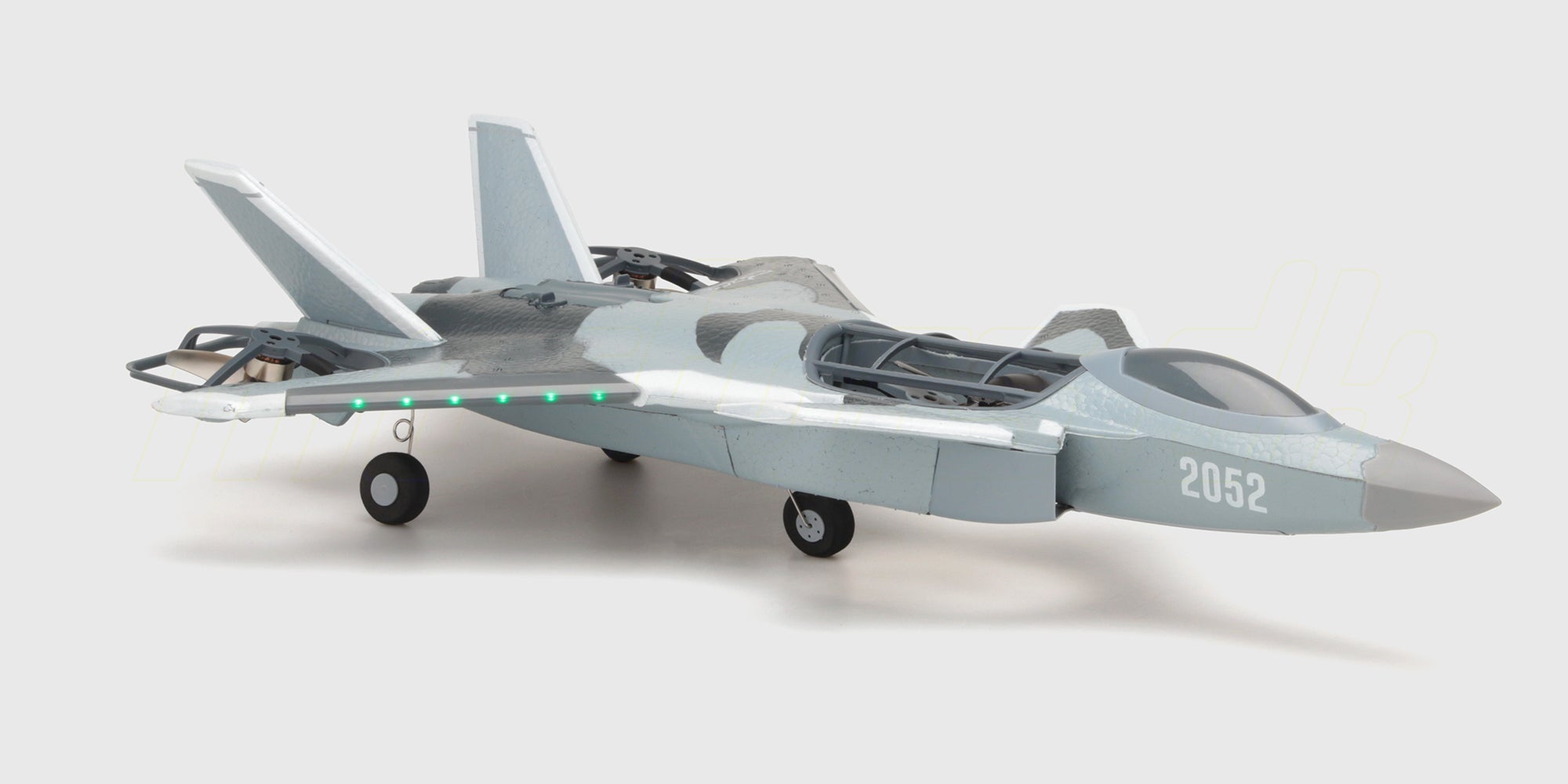 Grå Fighter Jet Brushless fjernstyret fly med camouflage mønster set nedefra under flyvning mod en blå himmel.