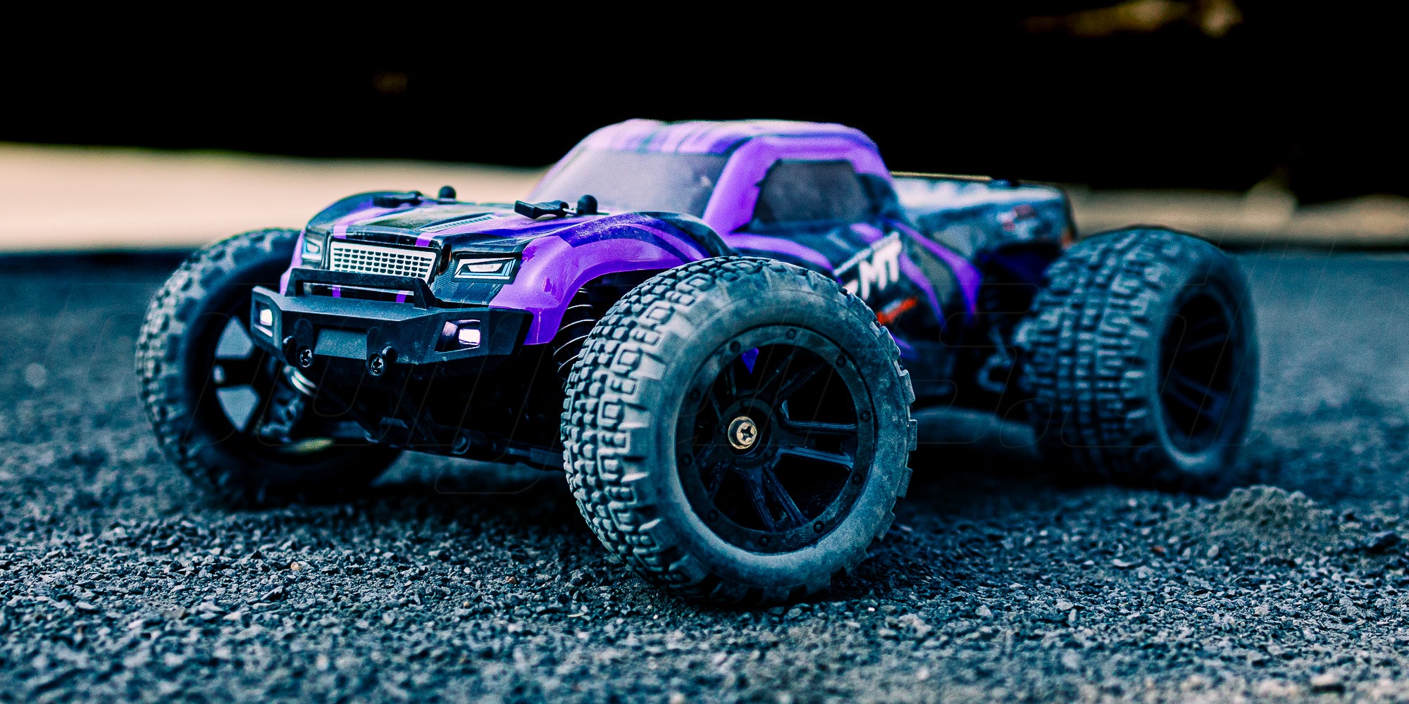 Grøn og sort Hunter MT10 fjernstyret bil kører i høj fart på en grusvej og hvirvler støv op.