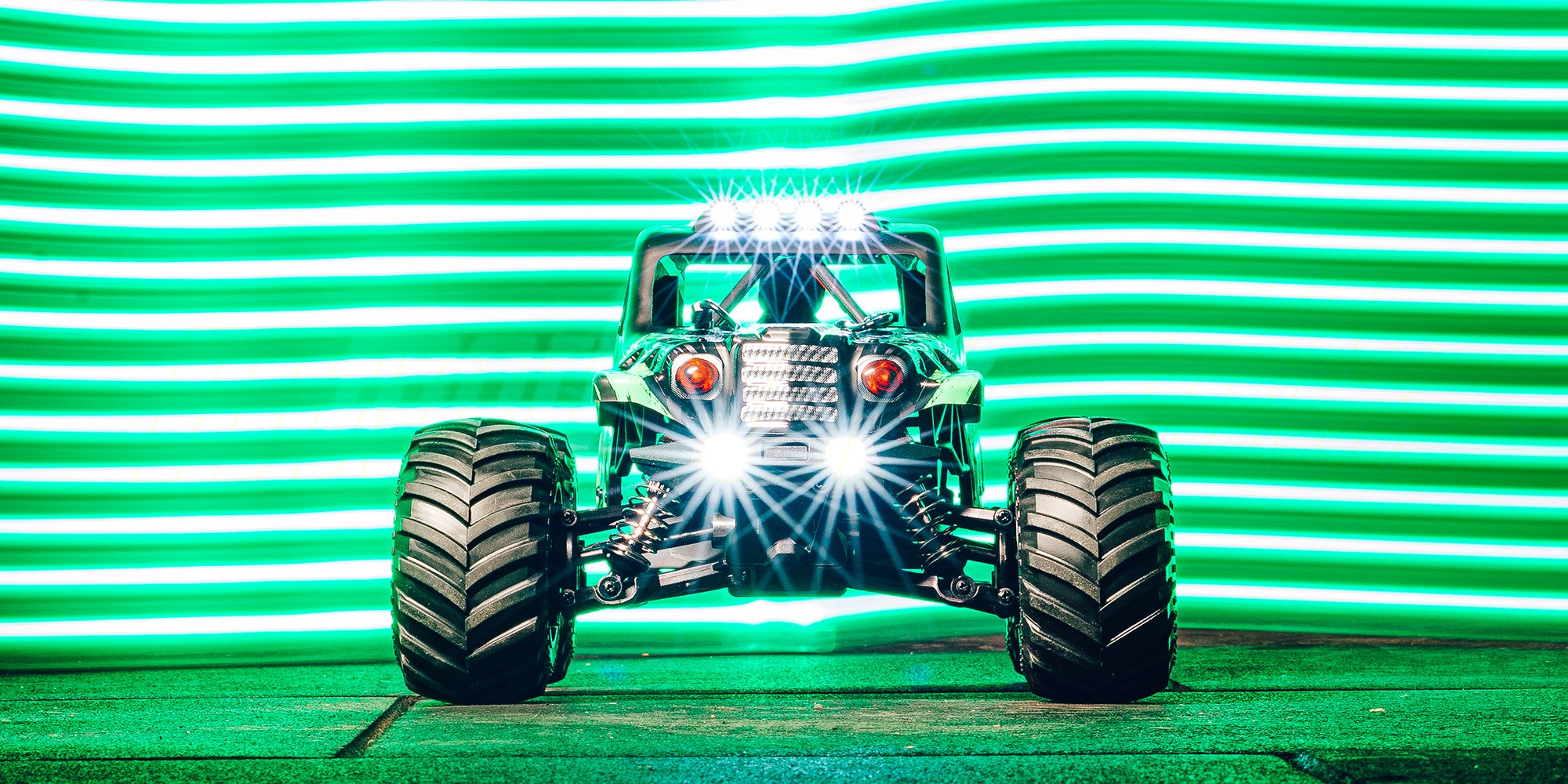 Grøn Hurricane XL Monster Truck med store hjul kører gennem mudder på en offroad bane.