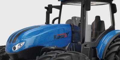 Grøn fjernstyret traktor med frontlæsser og store baghjul i bevægelse på en græsmark.