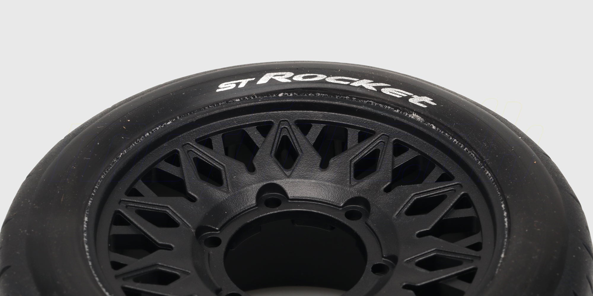 To sorte ST-Rocket dæk med hvide fælge og groft mønster til fjernstyrede stadium trucks set forfra.