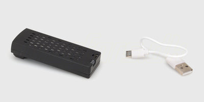 Opladning af batteri til Drone M6 Zoomer via USB-ladekabel vist på hvid baggrund.