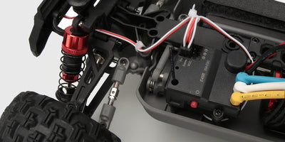 HyperGo Brushless SE fjernstyret bil i fuld fart på en grusvej med støvskyer bag de store offroad-hjul.