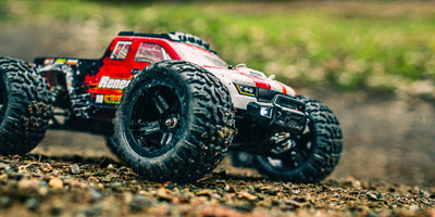 Tornado Brushless fjernstyret bil i fuld fart på en grusvej med støvskyer bag de fire hjul.