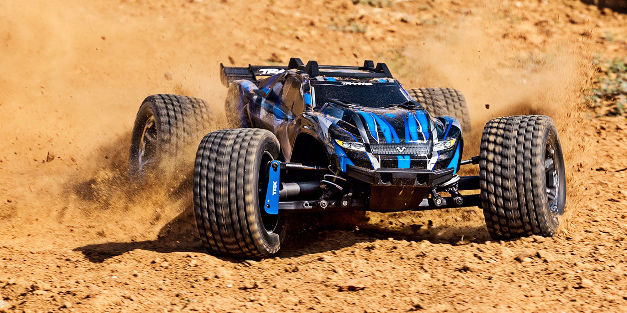Blå Traxxas Rustler 4x4 Ultimate fjernstyret bil med offroad-dæk vist skråt forfra på hvid baggrund.