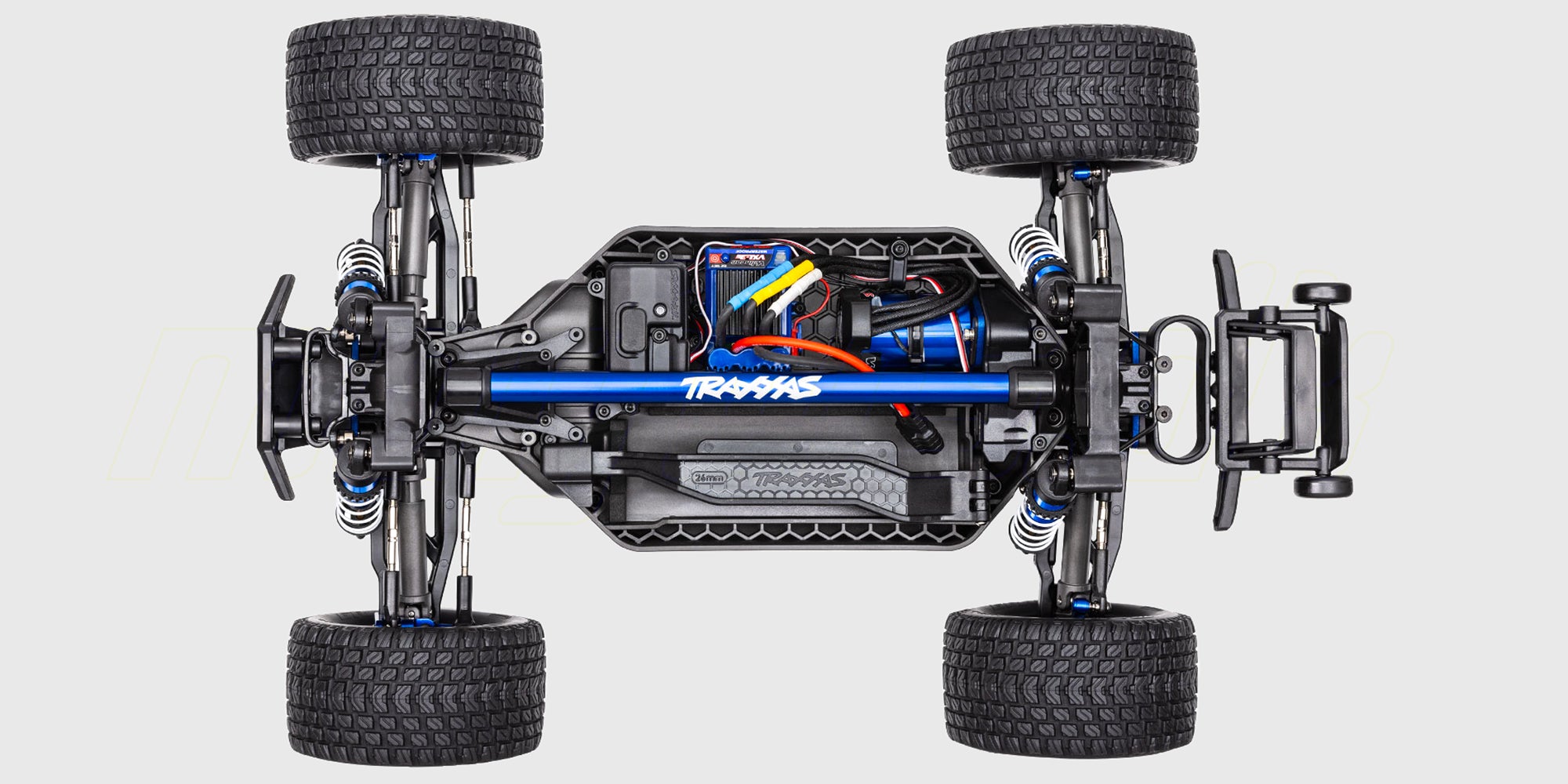 Blå Traxxas Rustler 4x4 Ultimate stadium truck i fuld fart på løst underlag.