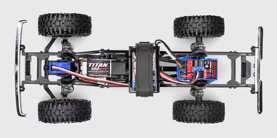 Brun Traxxas TRX-4M Ford F-150 fjernstyret crawler kører over sten i bakket terræn.