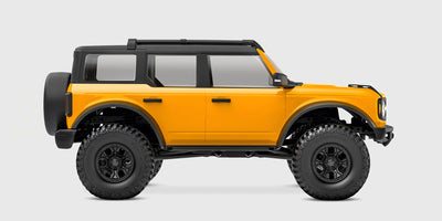 Orange Traxxas TRX-4M Ford Bronco crawler i 1:18 skala set forfra på hvid baggrund.