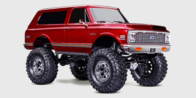En rød Traxxas TRX-4 Chevrolet K5 Blazer fjernstyret crawler forcerer store sten og ujævnt terræn.
