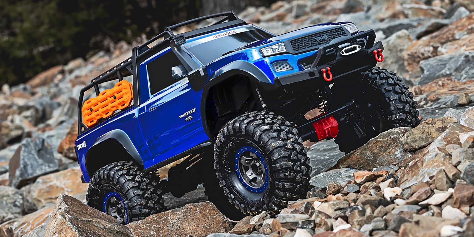Rød Traxxas TRX-4 Sport High Trail crawler med store offroad-hjul kører gennem vand og mudret terræn.