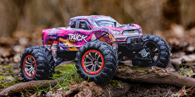 Rød XLH Race Truck fjernstyret bil kører gennem visne blade på en skovbund.