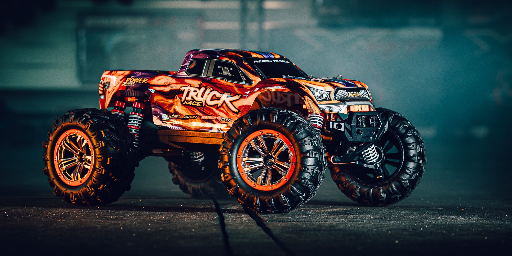 Orange XLH Race Truck fjernstyret bil i fuld fart gennem terrænet udendørs.