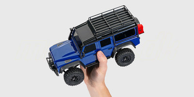 TRX-4M Defender fjernstyret bil i skala 1:18 holdt i en hånd for at vise den kompakte størrelse og detaljer.