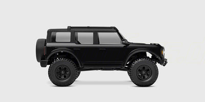 Sort Traxxas TRX-4M Ford Bronco fjernstyret bil set fra siden på hvid baggrund.