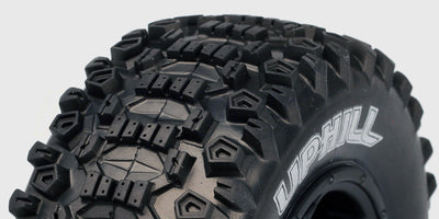 To sorte SC-Uphill dæk med groft offroad mønster monteret på hvide fælge til fjernstyret bil.