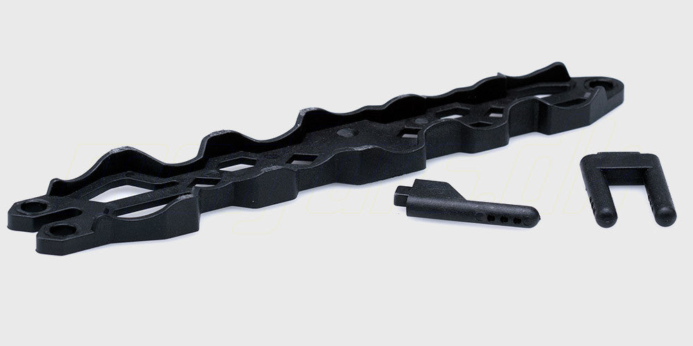 Sort batteriholder og monteringspinde til fjernstyret bil vist på en hvid baggrund.