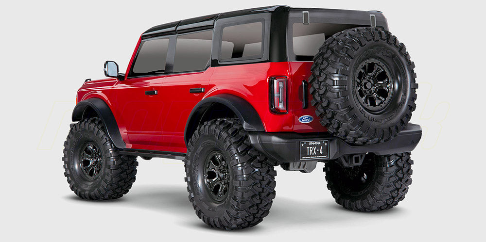 Traxxas TRX-4 Ford Bronco crawler i rød lakering forserer ujævnt terræn i naturen.