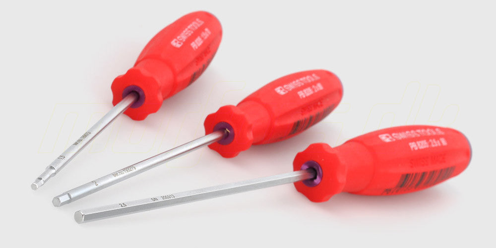 Tre SwissGrip unbracoskruetrækkere i forskellige størrelser med ergonomiske sorte og røde håndtag.